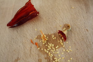 Removing the seeds will keep the harissa from becoming super-hot. Plus the seeds don't grind up as well as the pods.